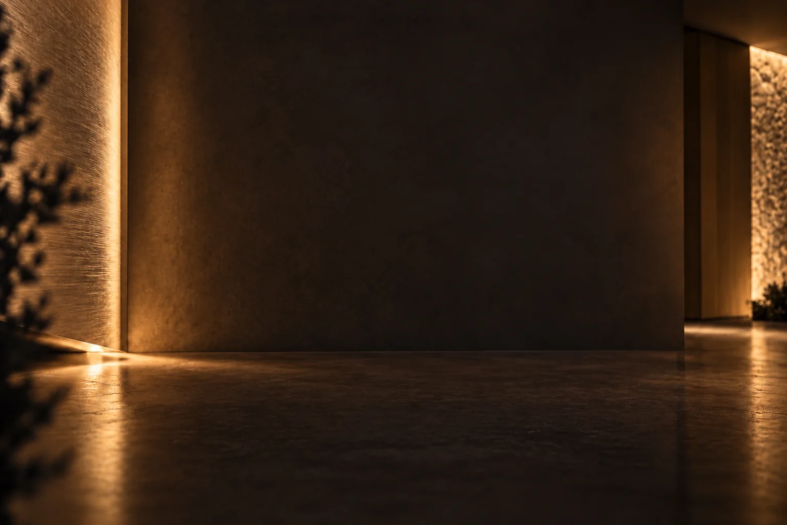 Warm concealed lighting on bronze-toned walls and a reflective floor in a dark architectural interior.