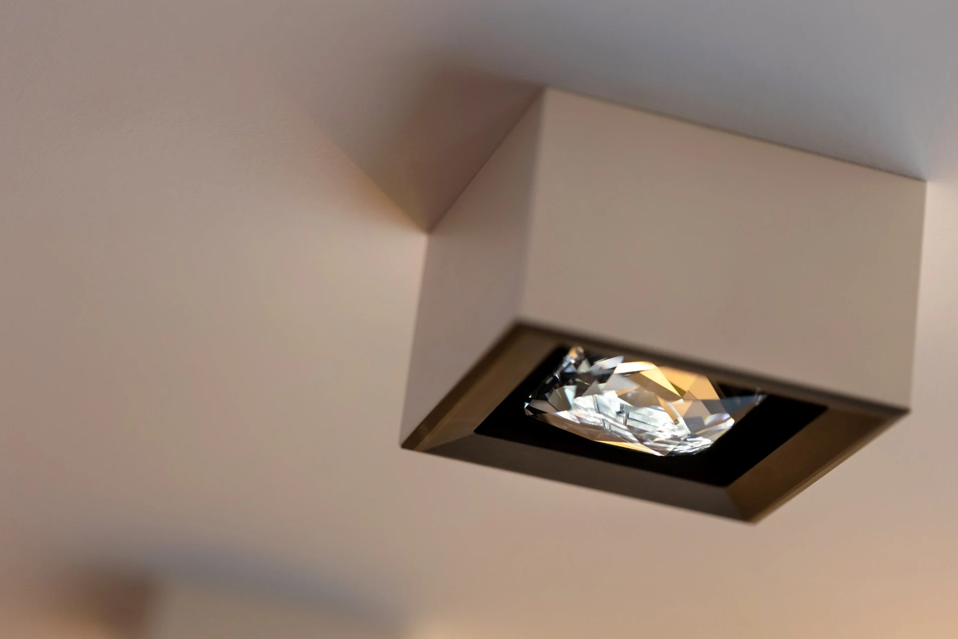 Side view of a ceiling-mounted MOIRA IRIS crystal spotlight with a white housing, bronze front and projecting faceted crystal.