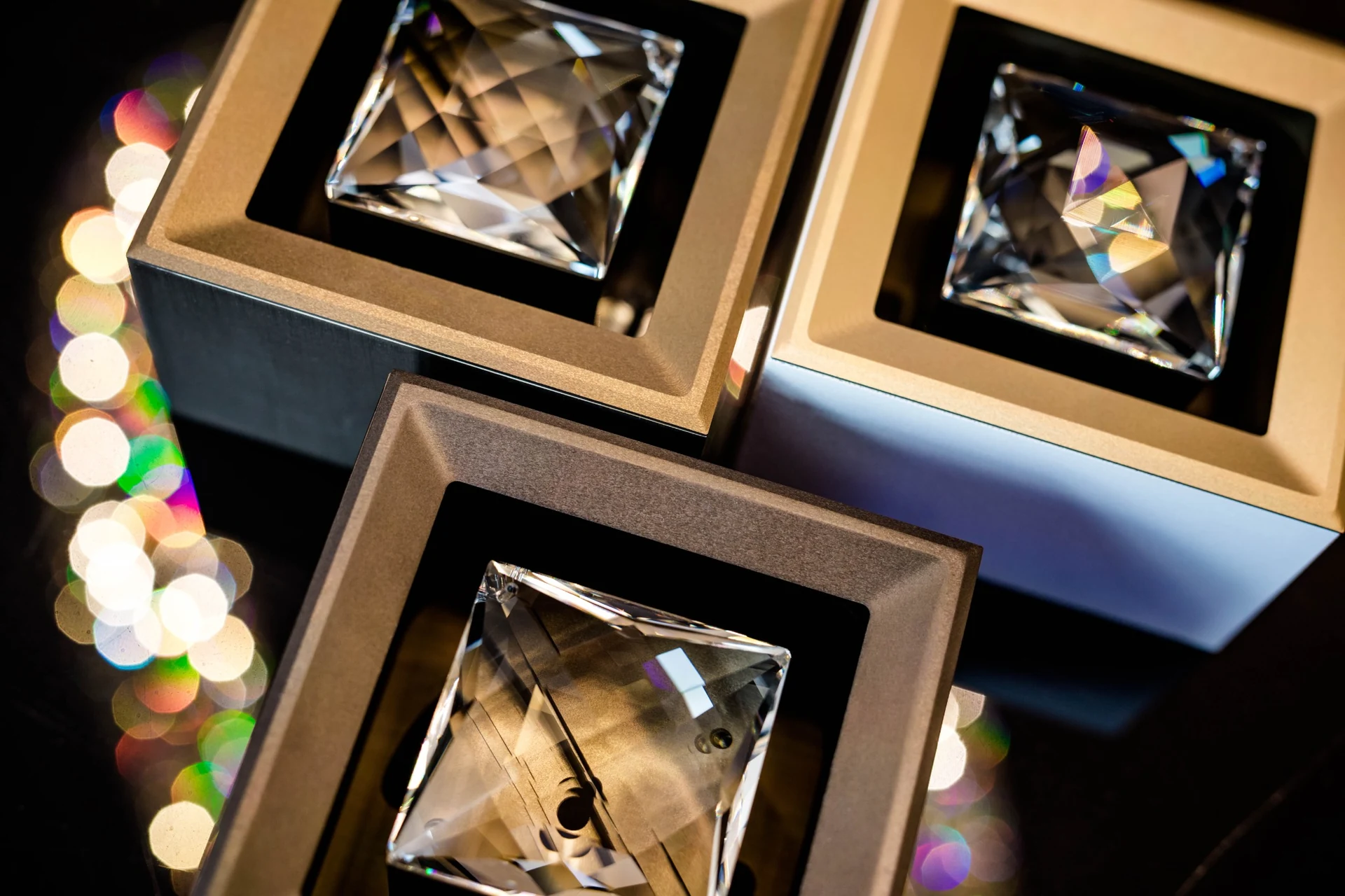 Three MOIRA IRIS crystal spotlights in contrasting finishes, viewed from above with colourful light reflections.