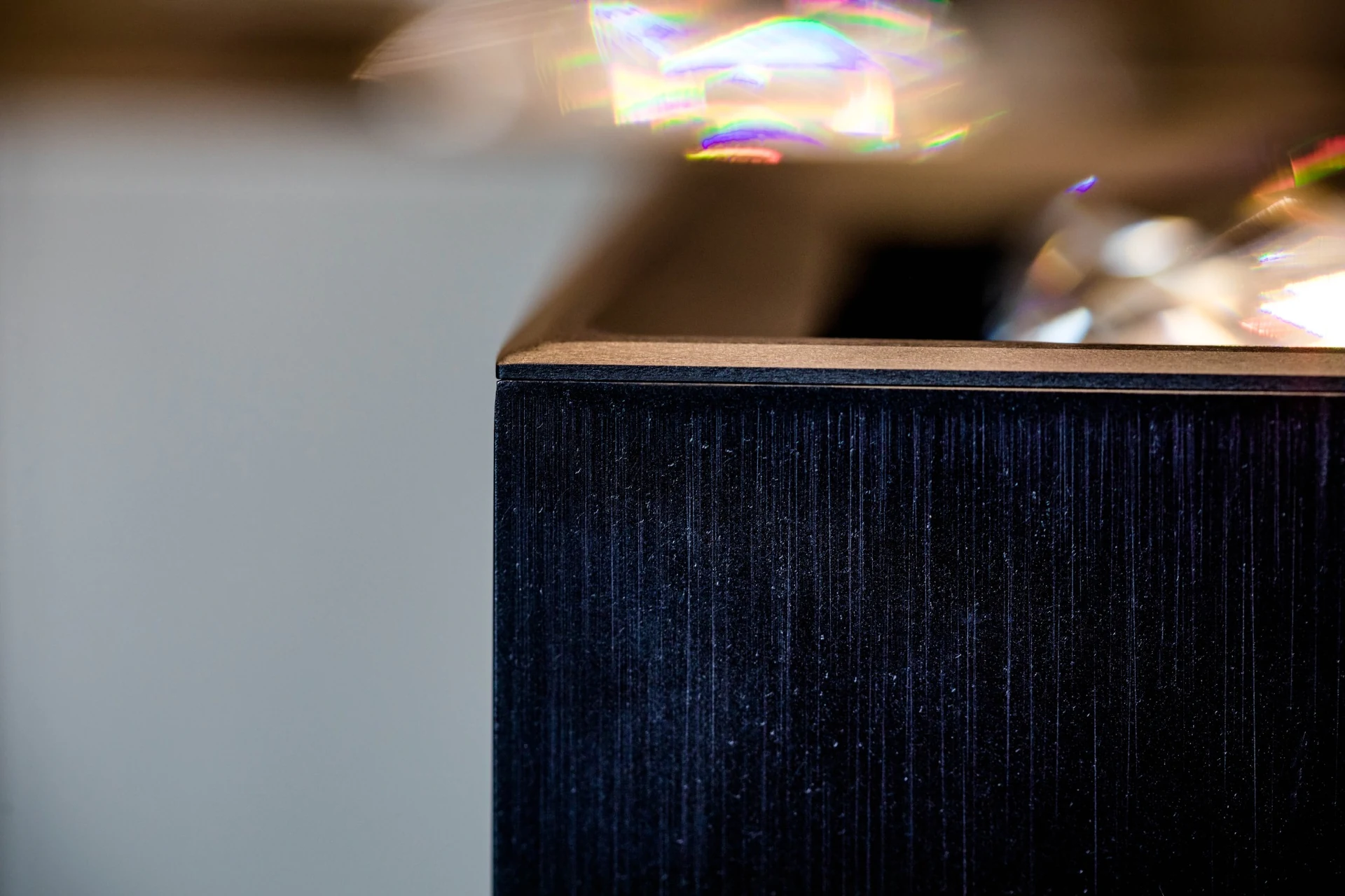 Close-up of the dark brushed side wall and bronze-toned upper rim of a MOIRA IRIS crystal spotlight.