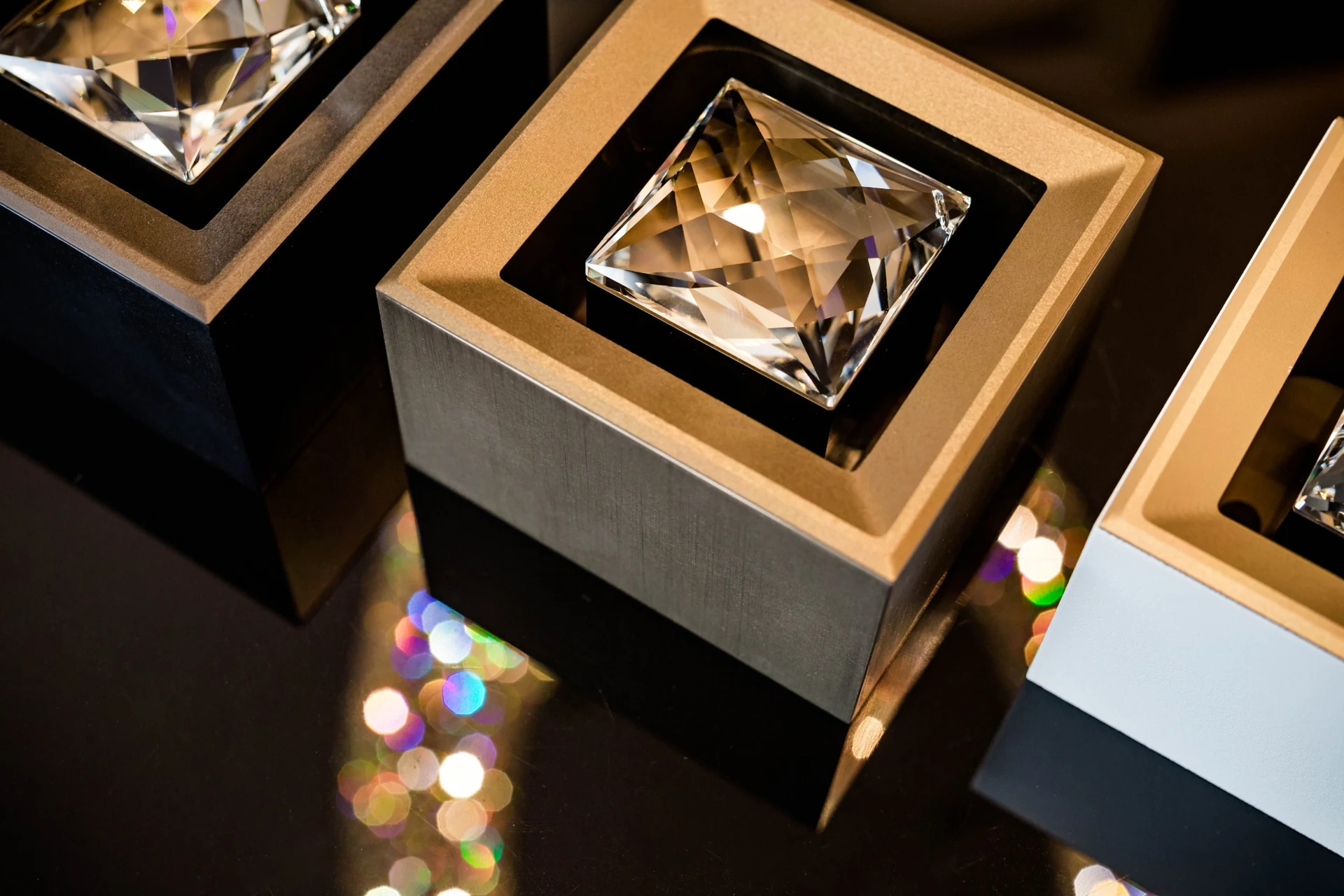 MOIRA IRIS crystal spotlights with bronze fronts and dark, brushed and white side-wall finishes.
