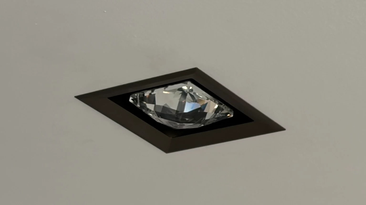 Recessed MOIRA IRIS ceiling spotlight with a dark bronze frame and projecting faceted crystal.